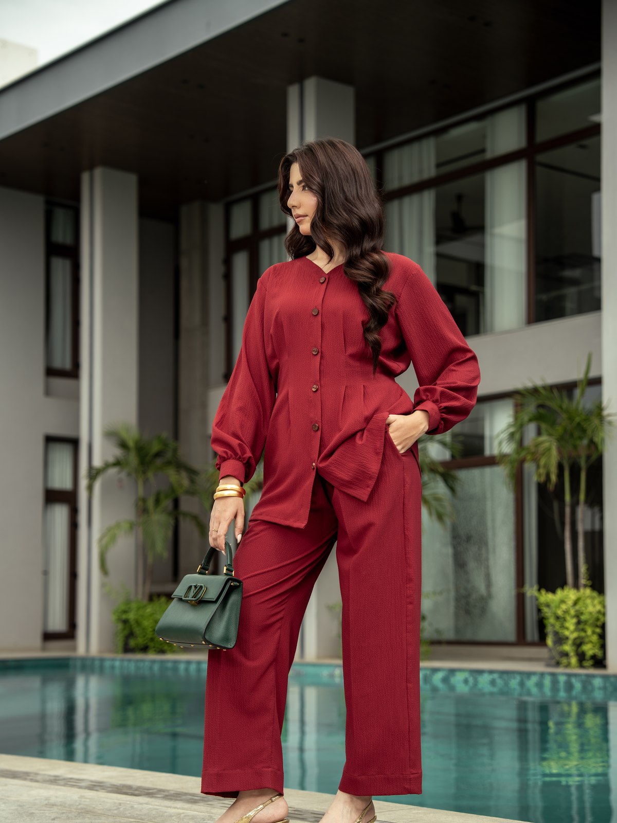 Ruby maroon co-ord beside the pool, one hand at the waist.