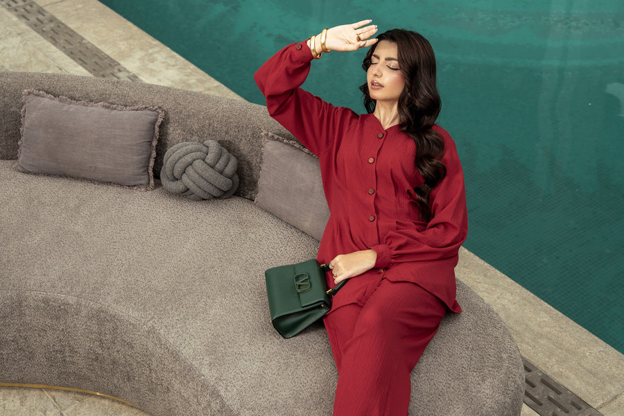Ruby co-ord seated on a curved bench beside the pool.